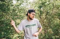 man wearing gray crew neck t shirt standing behind bush