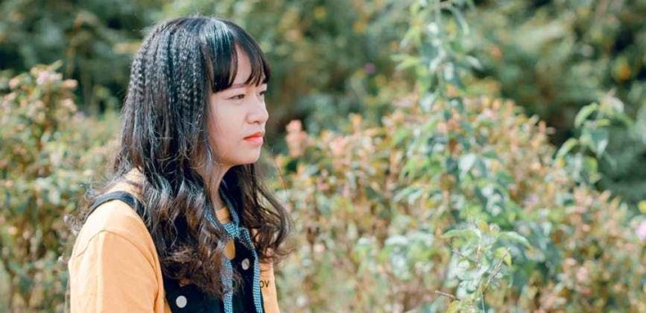 photo of woman sitting on ground surrounded by grass trees and plants sad unhappy not okay