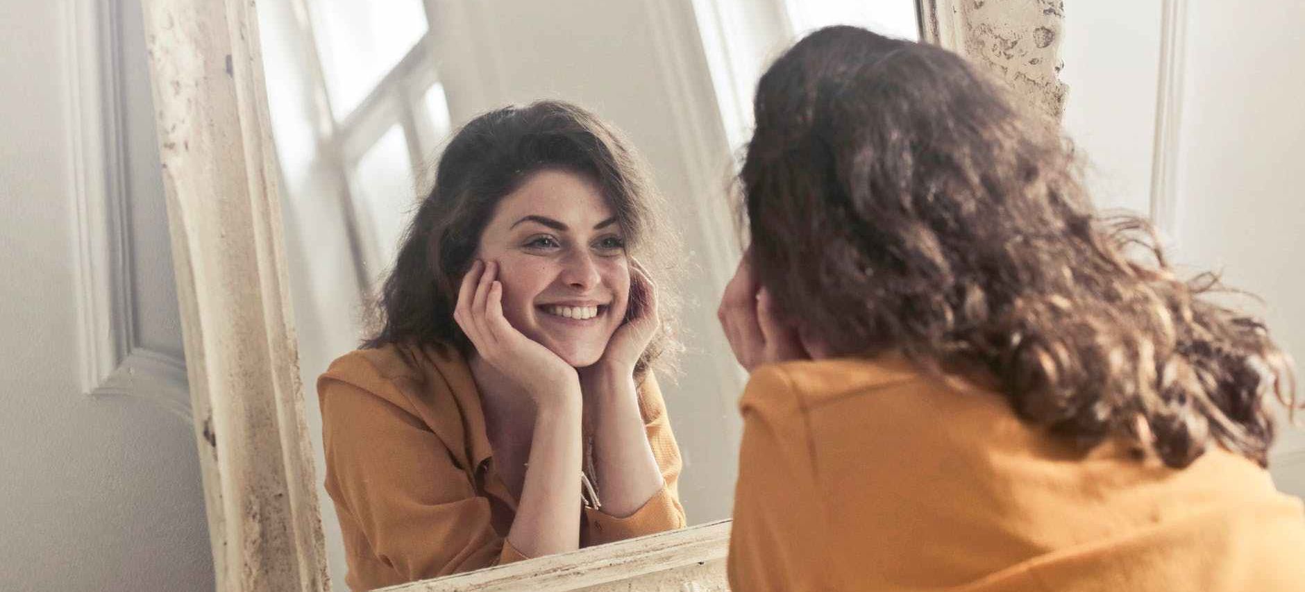 photo of woman looking at the mirror smiling