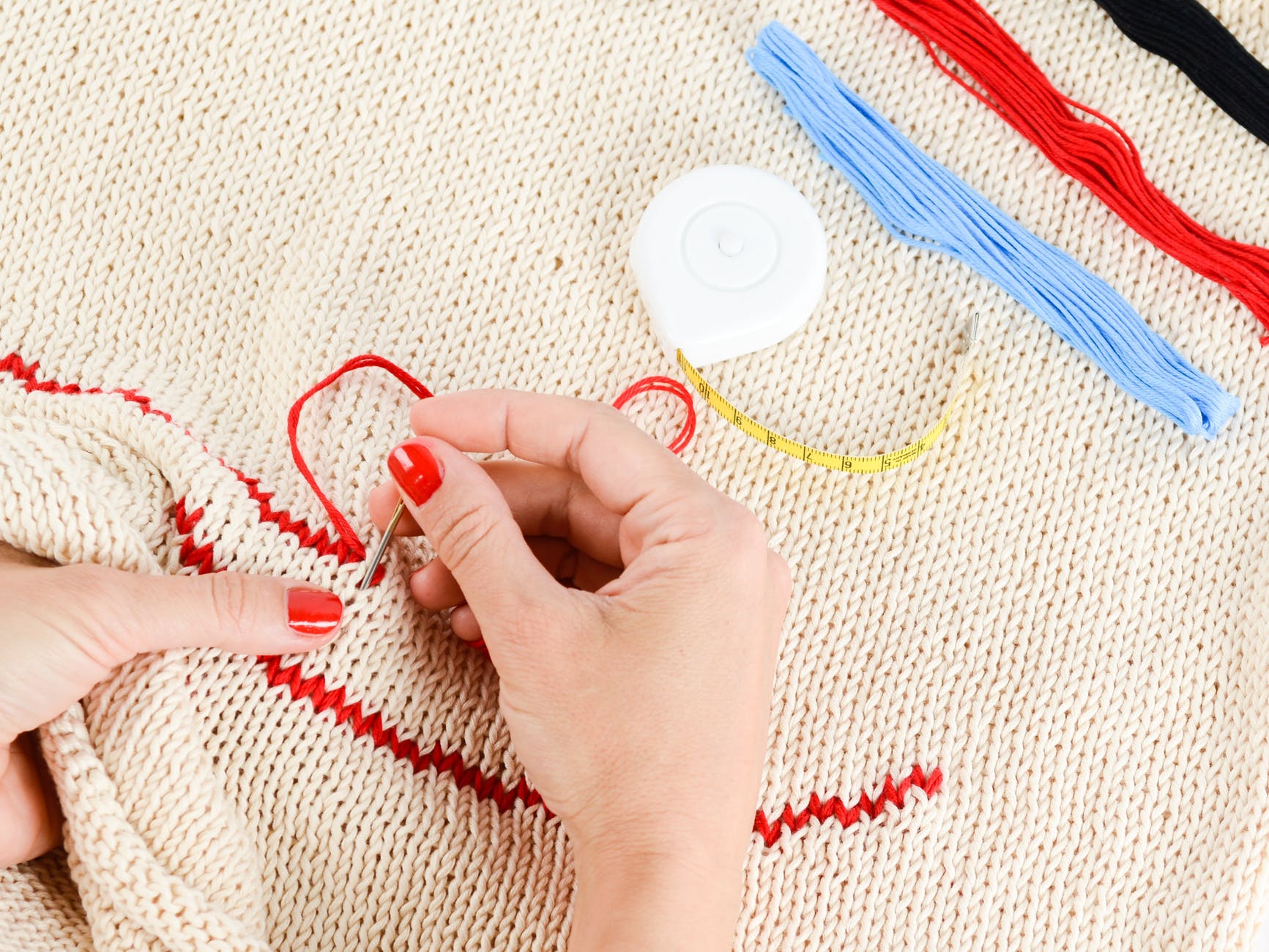 person embroidering a beige textile