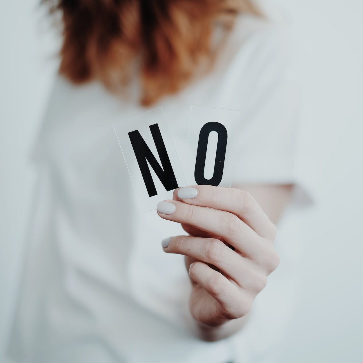 a hand holding a letter N and a letter O to make the word "no".