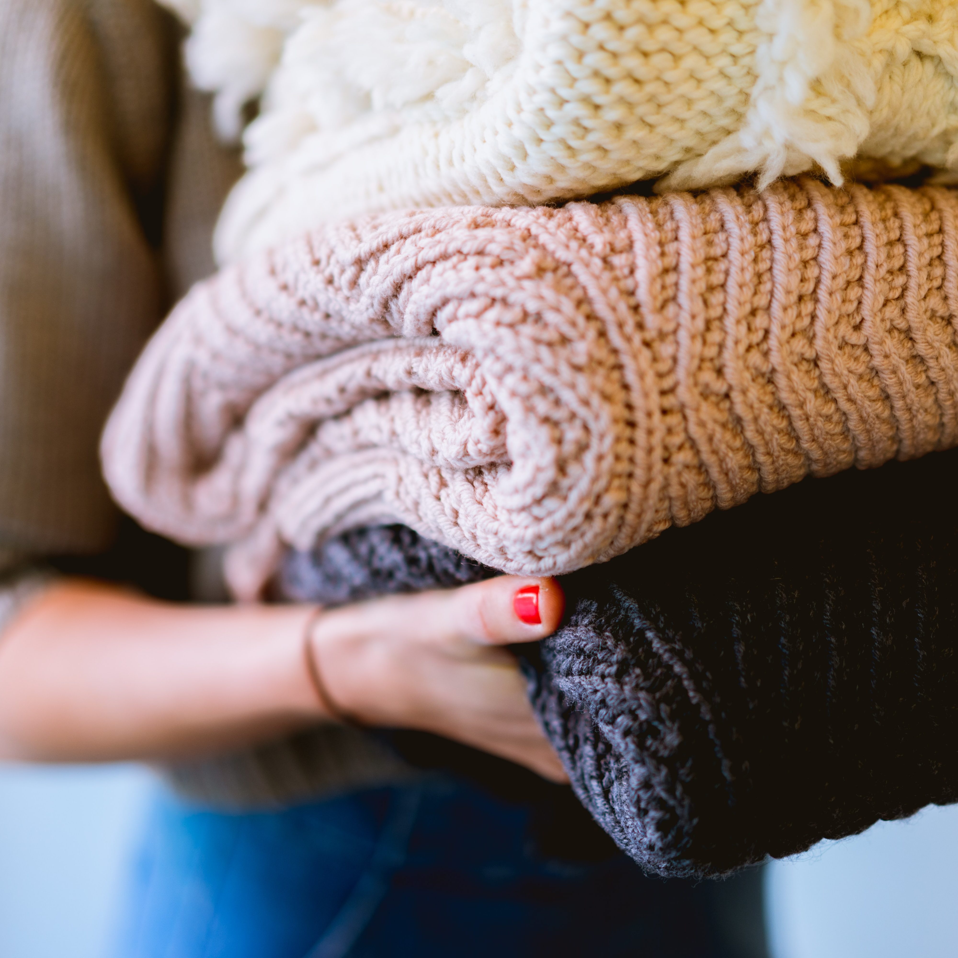 A woman holding a stack of woollen blankets  (wallflowerhaze.com)