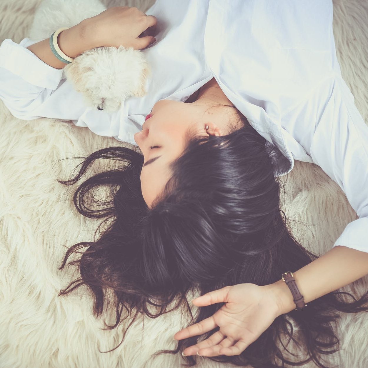 A woman lying down, cuddling her small dog. (wallflowerhaze.com)