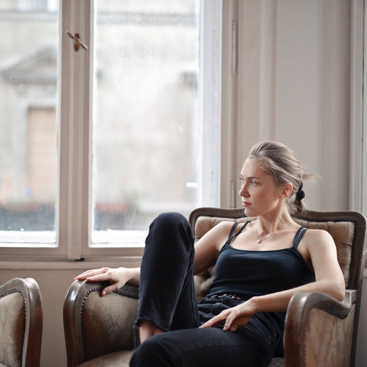 A woman sitting on a chair, staring off into the distance. (wallflowerhaze.com)