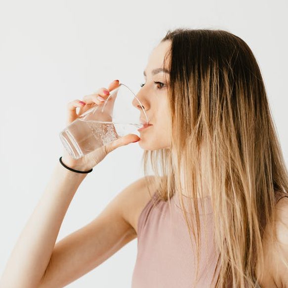 A woman drinking a glass of water. Sober October (wallfowerhaze.com)